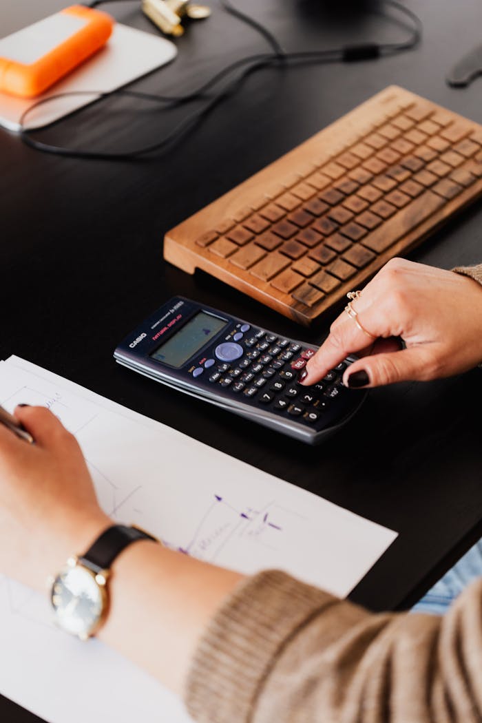 Mastering the First Impression: Your intriguing post title goes here From above crop anonymous female accountant working with calculator and writing down notes on paper while sitting at table with computer keyboard